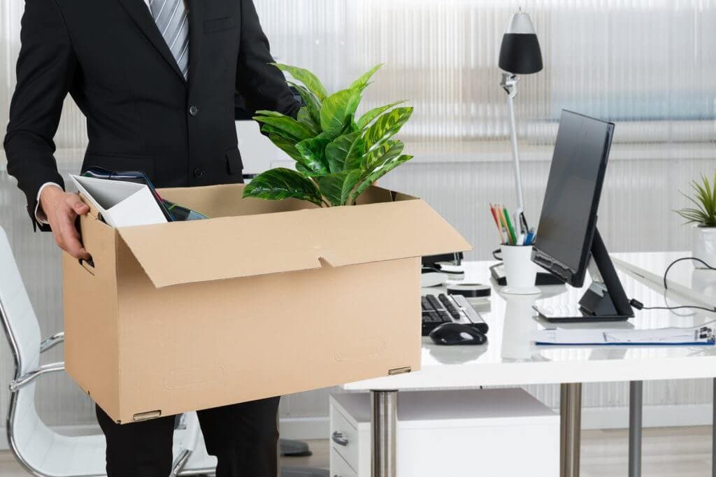 A guy in a suit holding box with office belongings