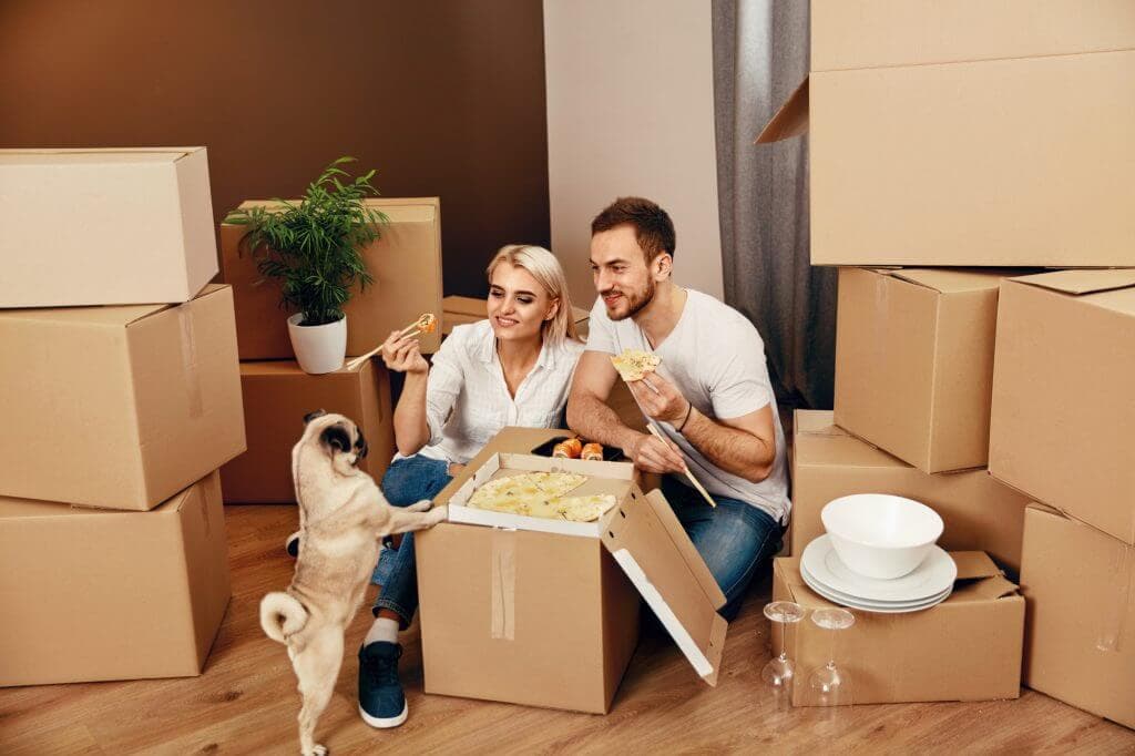 Happy couple with a dog eating pizza