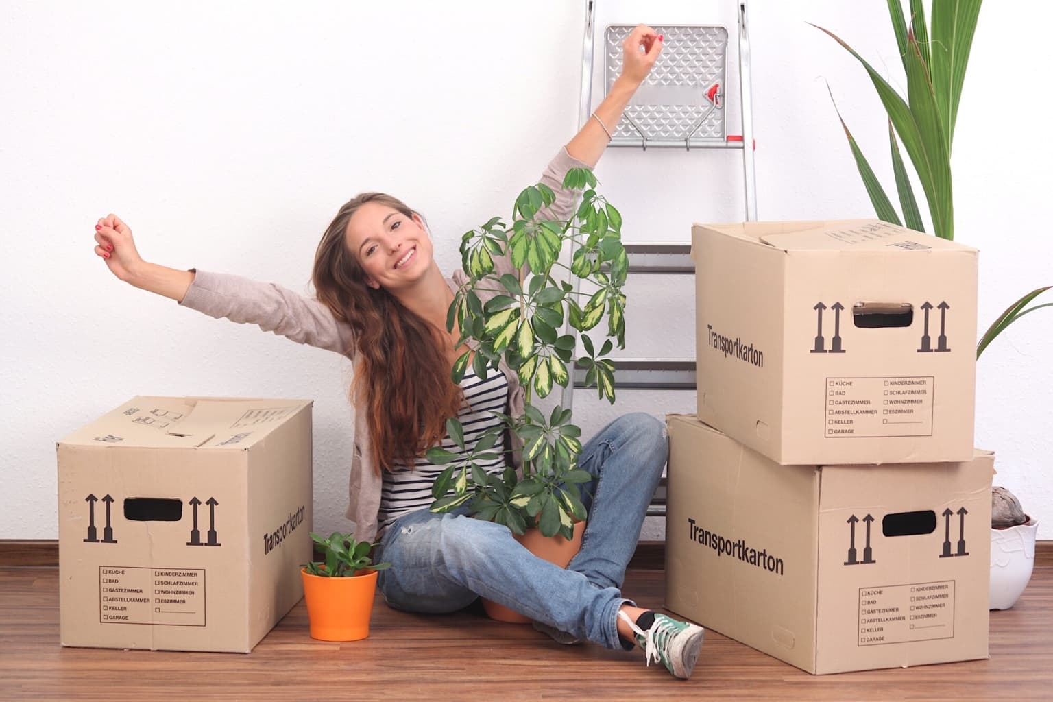 Happy woman surrounded by moving boxes and plants