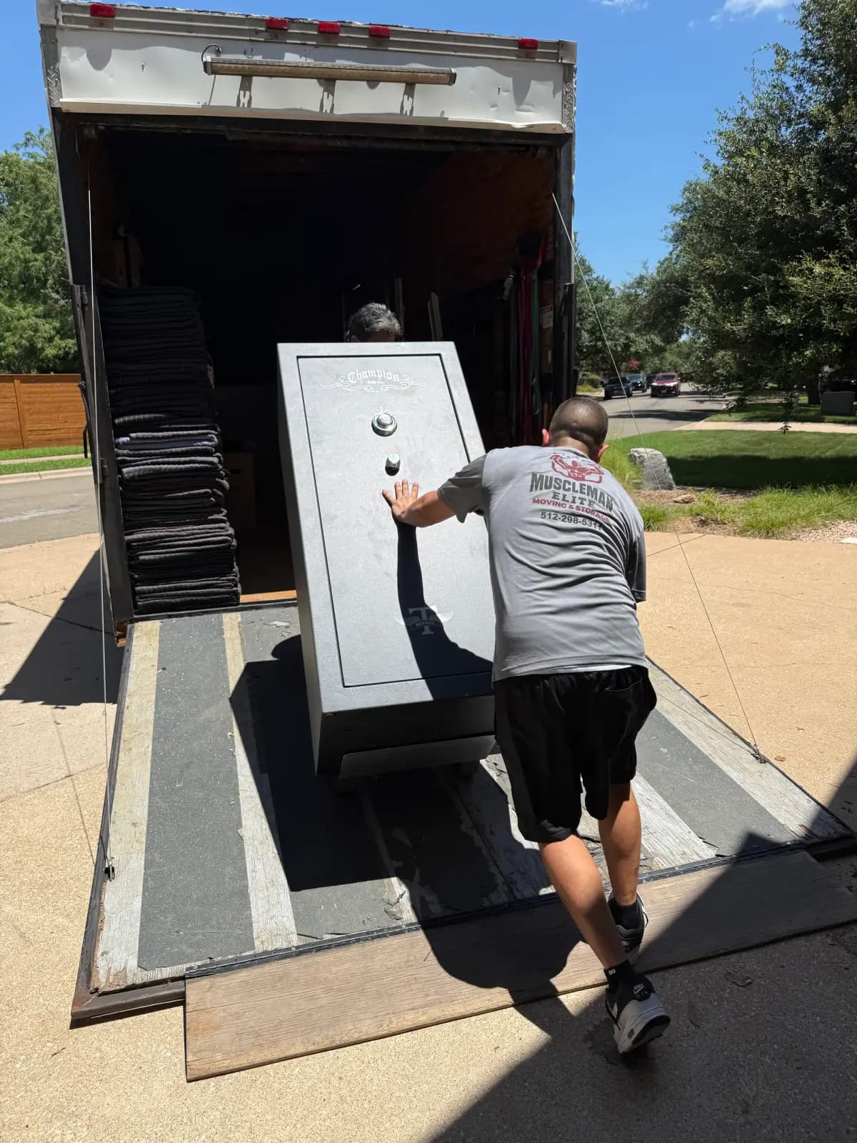 Muscleman Elite mover loading a large gun safe up the ramp into the moving truck