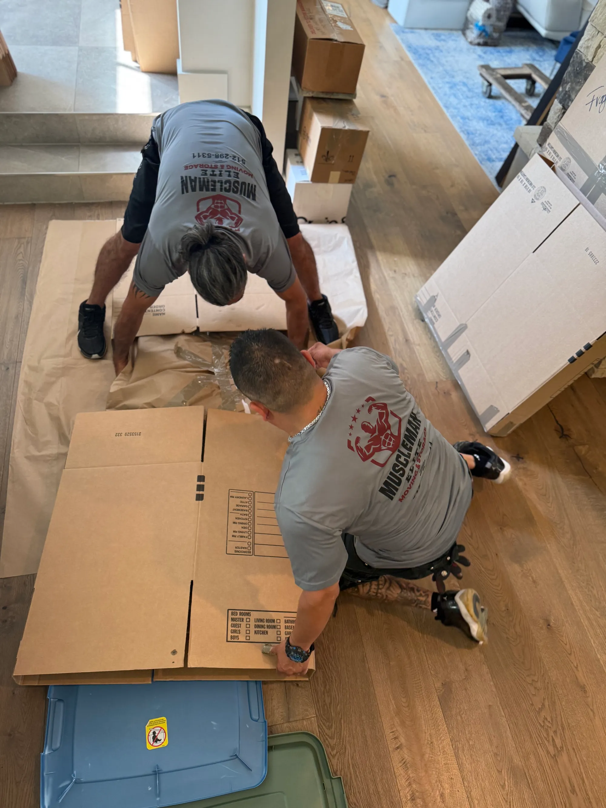 Muscleman Elite crew packing and labeling boxes on a floor-protected job site