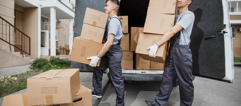 Two movers carrying boxes on the street