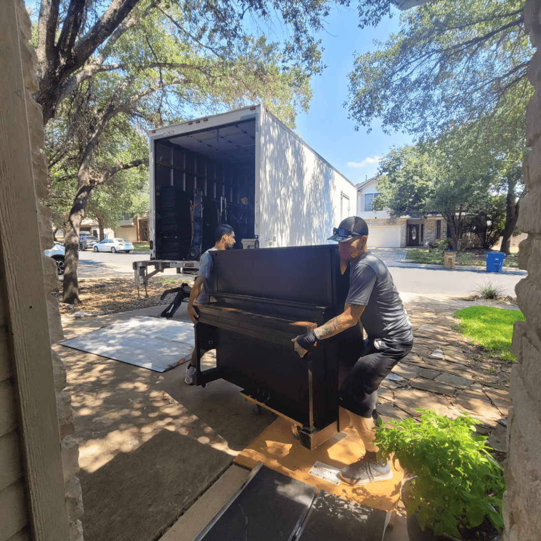 Piano movers navigating a tight doorway with an upright piano