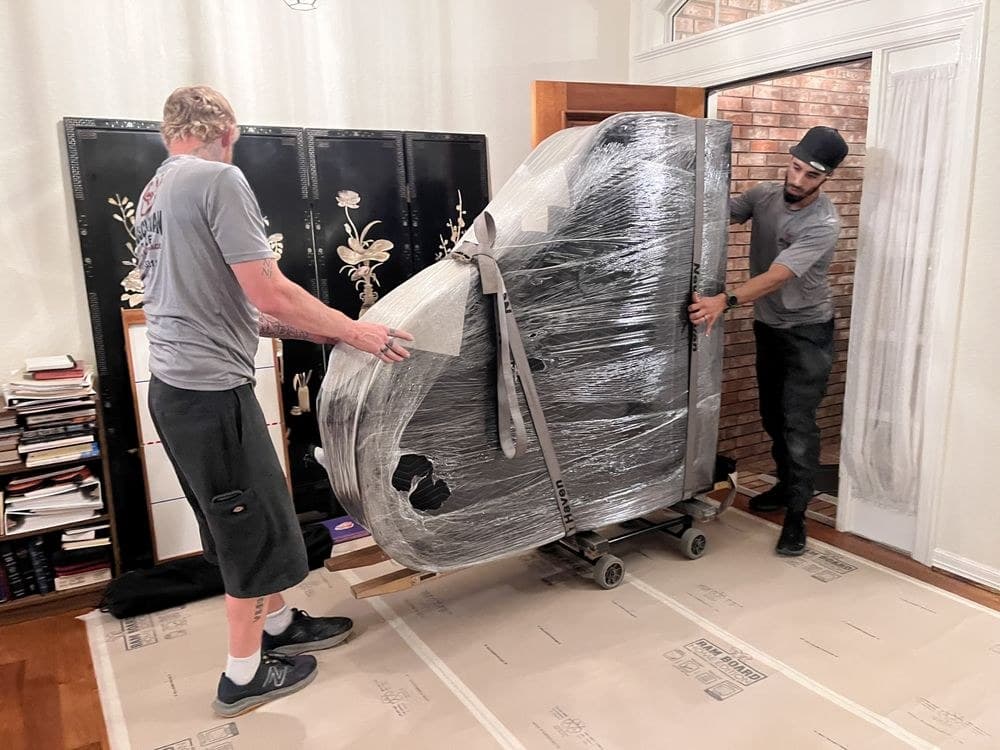 Muscleman Elite crew carrying a blanket-wrapped piano